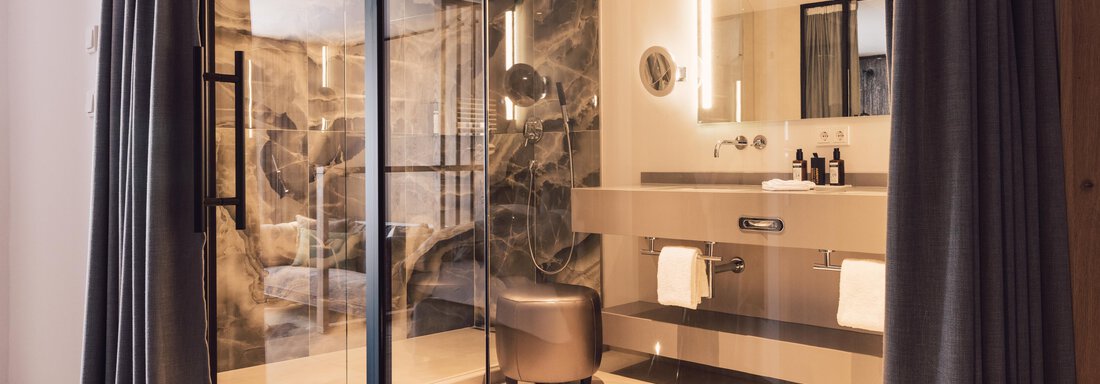 A modern bathroom with a glass shower and elegant furnishings. The walls are stylishly designed, and the light is pleasant. - 4 * Superior Hotel Schöne Aussicht - Hochsölden