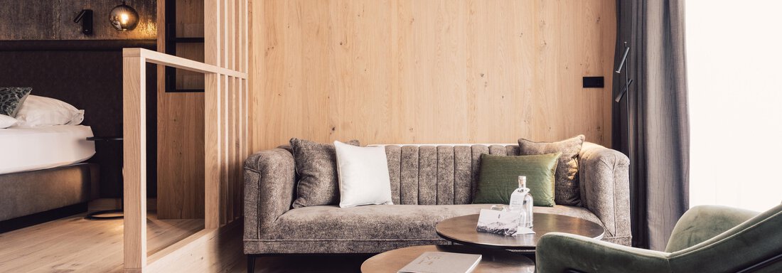 A modern living room with a gray sofa and a green armchair. The room has wooden paneling and large windows that let in plenty of light. - 4 * Superior Hotel Schöne Aussicht - Hochsölden