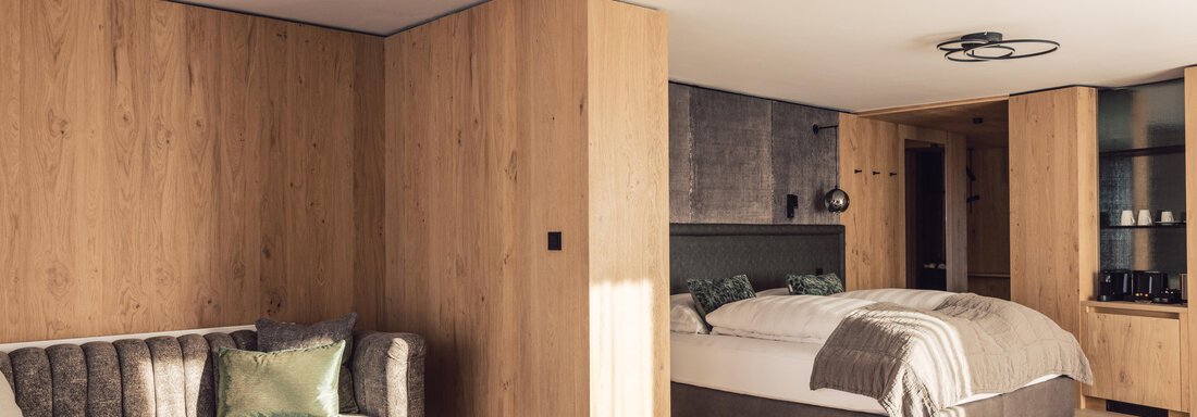 A modern room with wooden paneling, a large bed, and a cozy living area. The atmosphere is warm and inviting. - 4 * Superior Hotel Schöne Aussicht - Hochsölden