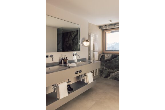 A modern bathroom with two sinks and a large mirror. Large windows offer a view of the mountains. - 4 * Superior Hotel Schöne Aussicht - Hochsölden