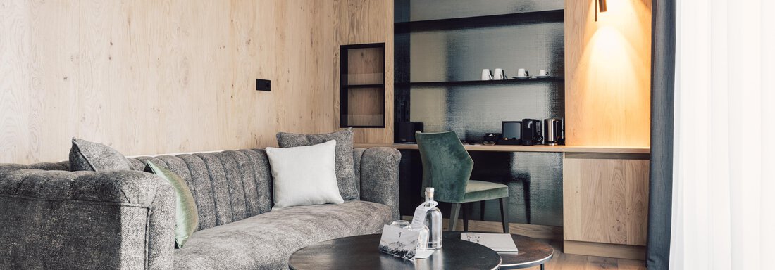 schoene_aussicht_w22_danielzangerl _567 A modern living room with a gray sofa and a round table. In the background, wooden shelves and a small coffee kitchen are visible. - 4 * Superior Hotel Schöne Aussicht - Hochsölden