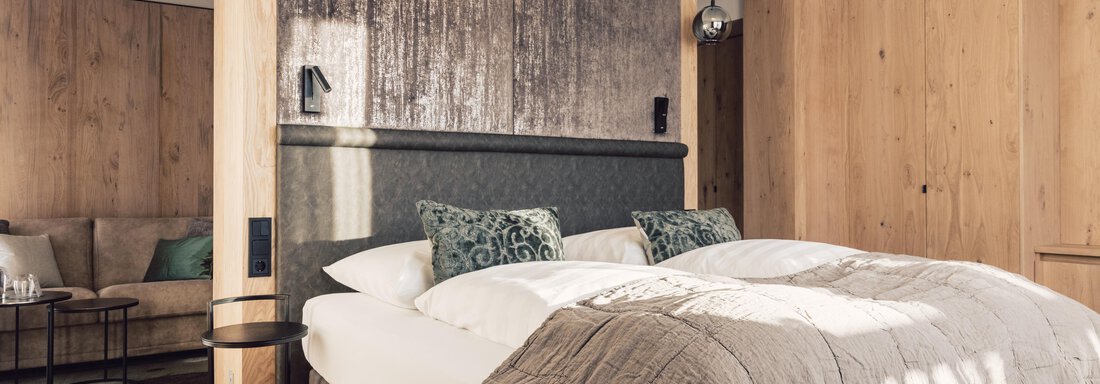 A modern bedroom with a large bed and stylish wooden walls. The decor is cozy and minimalist, ideal for relaxation. - 4 * Superior Hotel Schöne Aussicht - Hochsölden