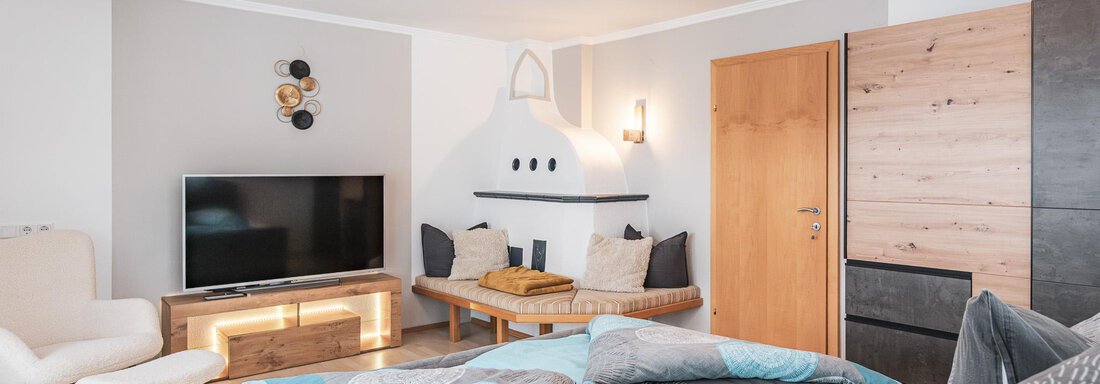 Doppelbett mit Kachelofen im Zimmer - APART Naturcamping Kuprian - Huben