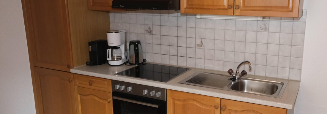 Küchenblock | © Ewald Auer (CC C) A modern kitchen with wooden furniture and a bright countertop. It is equipped with a stove, a sink, and various kitchen appliances. - Appartements Gufler - Huben