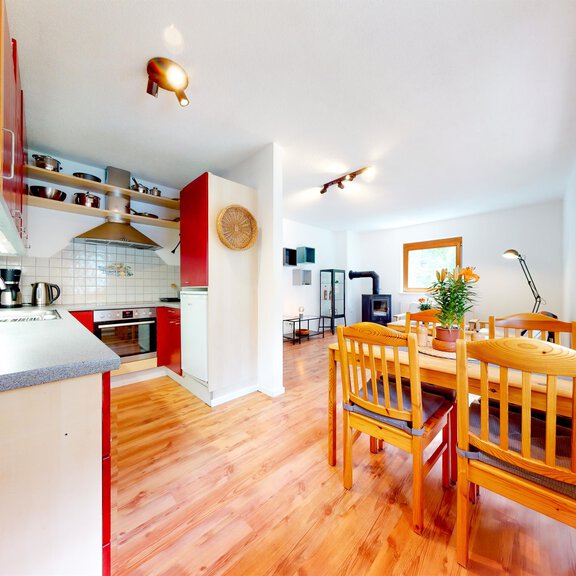 A bright and modern kitchen with dining area. The room has wooden flooring and large windows that let in plenty of light. - Ferienwohnung Kathrin - Huben