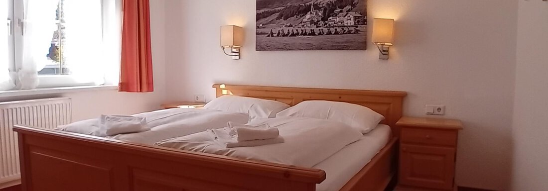 1 Schneeglöckchen_Zweibettzimmer A cozy bedroom with a large bed and wooden details. The walls are painted in light colors, with a window that lets in daylight. - Haus Christoph im Herzen des Ötztals - Huben