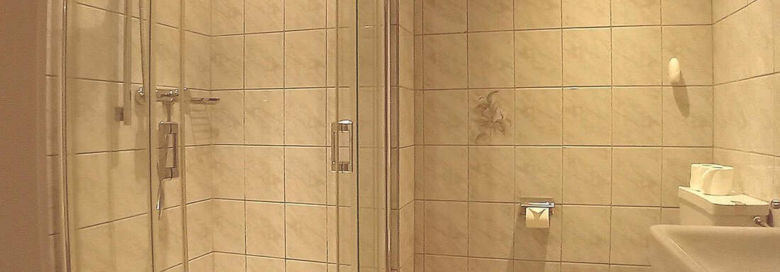 A modern bathroom with a glass shower and a toilet. The walls are adorned with light tiles. - Haus Christoph im Herzen des Ötztals - Huben