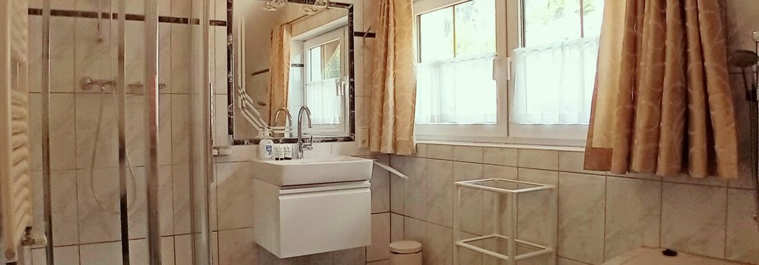 A modern bathroom with a shower, a sink, and a bathtub.  
Bright tiles and windows create a friendly atmosphere. - Haus Christoph im Herzen des Ötztals - Huben