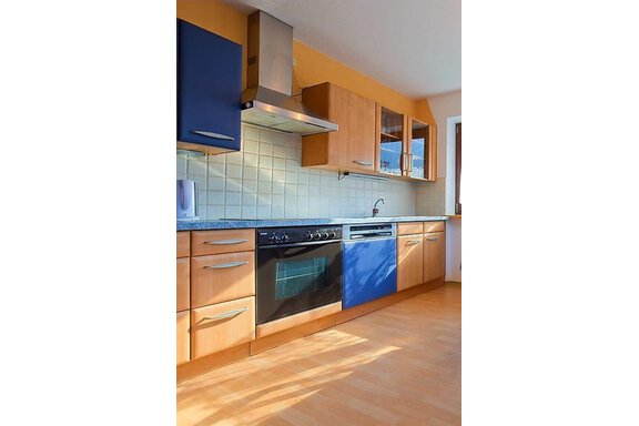Eine moderne Küche mit Holz- und blauen Schränken. Die Arbeitsfläche ist aus Granit und es gibt moderne Haushaltsgeräte. - Haus Max - Huben