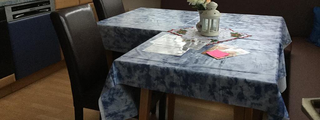 Ein gemütlicher Essbereich mit einem Tisch und Stühlen. Auf dem Tisch steht eine Blumenvase und einige Notizen sind verteilt. - Haus Max - Huben