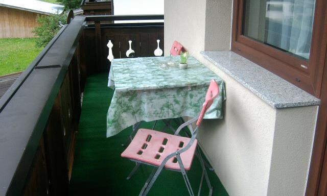 Ein Balkon mit einem Tisch und einer Klappstuhl. Der Tisch ist mit einem grünen Tuch bedeckt und es gibt einen kleinen Pflanzenbehälter darauf. - Haus Max - Huben