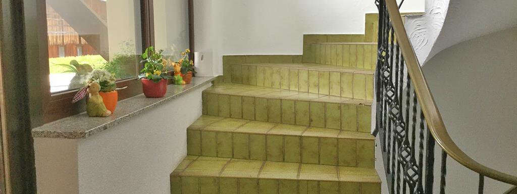 Eine Treppe mit grünen Fliesen führt nach oben. Neben der Treppe stehen kleine Pflanzen in Töpfen. - Haus Max - Huben