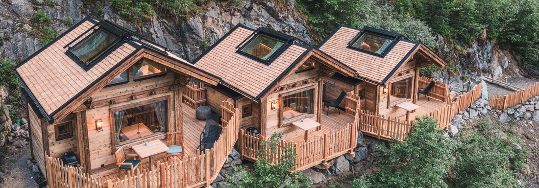 Drei gemütliche Holzhütten in der Natur, umgeben von Bäumen. Jede Hütte hat eine Terrasse mit einem schönen Blick auf die Umgebung. - Naturcamping Kuprian - Ötztal - Huben