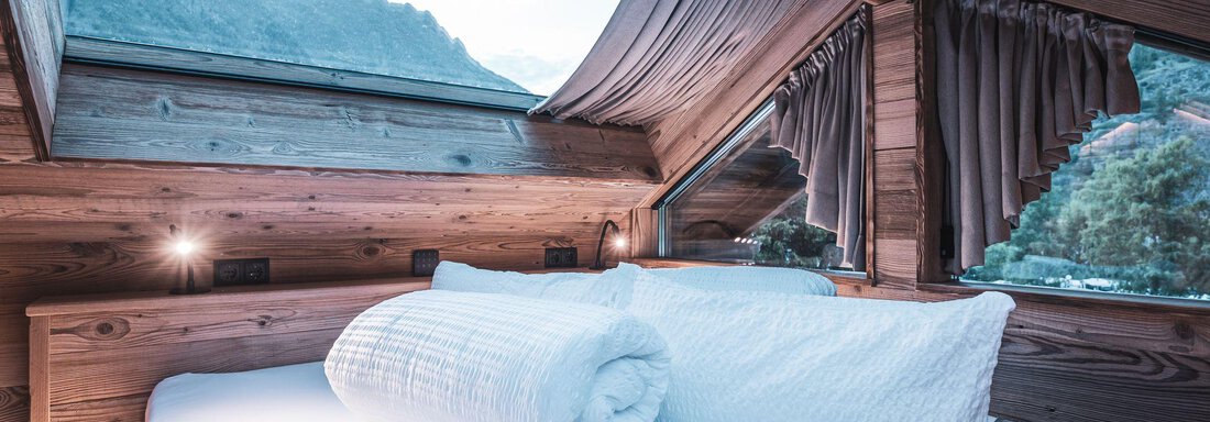 Ein gemütliches Schlafzimmer mit Holzwänden und großen Fenstern. Von dort hat man einen Blick auf die Berge und die Natur. - Naturcamping Kuprian - Ötztal - Huben