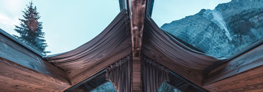 Ein gemütliches Schlafzimmer mit Holzdesign und einem großen Fenster. Der Blick geht auf eine beeindruckende Berglandschaft und einen klaren Himmel. - Naturcamping Kuprian - Ötztal - Huben