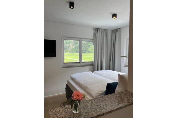 Ein modernes Schlafzimmer mit zwei Einzelbetten und neutralen Farben. Große Fenster bieten einen Blick auf die grüne Landschaft. - ONO Apartments - Huben