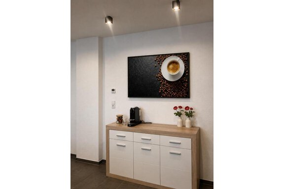 Eine moderne Küche mit einem Holzschrank und einer eleganten Kaffeekapselmaschine. An der Wand hängt ein Kunstwerk mit einer Tasse Kaffee und Kaffeebohnen. - ONO Apartments - Huben
