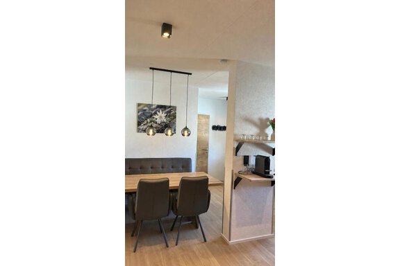 Ein modernes Esszimmer mit einem Holzstisch und vier Stühlen. Es gibt eine dekorative Wand mit einem Bild und Pendelleuchten über dem Tisch. - ONO Apartments - Huben