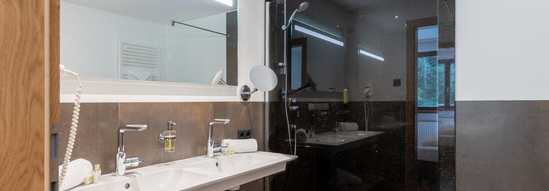 Ein modernes Badezimmer mit einer großen Dusche und zwei Waschbecken. Die Wände sind in schlichten Farbtönen gehalten und das Licht ist warm und einladend. - Alpenappartement Central Valley Penthouse - Längenfeld