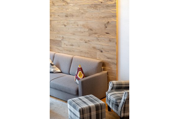 Ein gemütliches Wohnzimmer mit einem grauen Sofa und karierten Sesseln. Die Wände sind aus hellem Holz, was eine warme Atmosphäre schafft. - Alpenappartement Central Valley Penthouse - Längenfeld