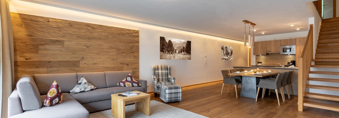 Riml_Sport_Längenfeld_Suit-20 Ein modernes Wohnzimmer mit einem gemütlichen Sofa und einem Holztisch. Im Hintergrund ist eine offene Küche und eine Treppe sichtbar. - Alpenappartement Central Valley Penthouse - Längenfeld