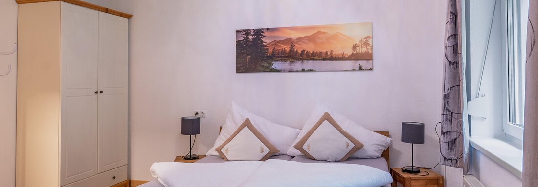 A cozy bedroom with a large bed and modern lighting. A picture of a landscape hangs on the wall, and there is a wardrobe as well as nightstands. - Apart Conny - Längenfeld