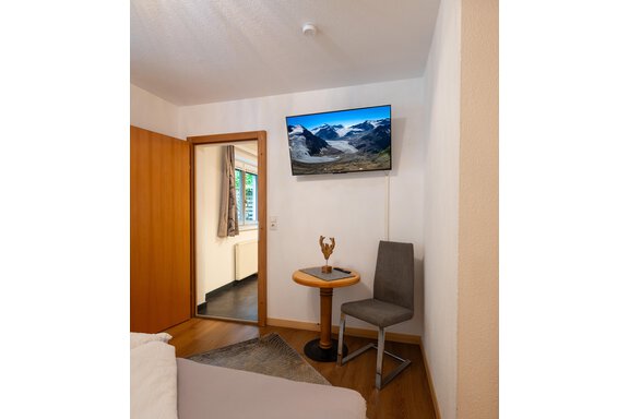 A cozy room with a television and a view of the mountains. A round table and a chair complement the furnishings. - Apart Conny - Längenfeld