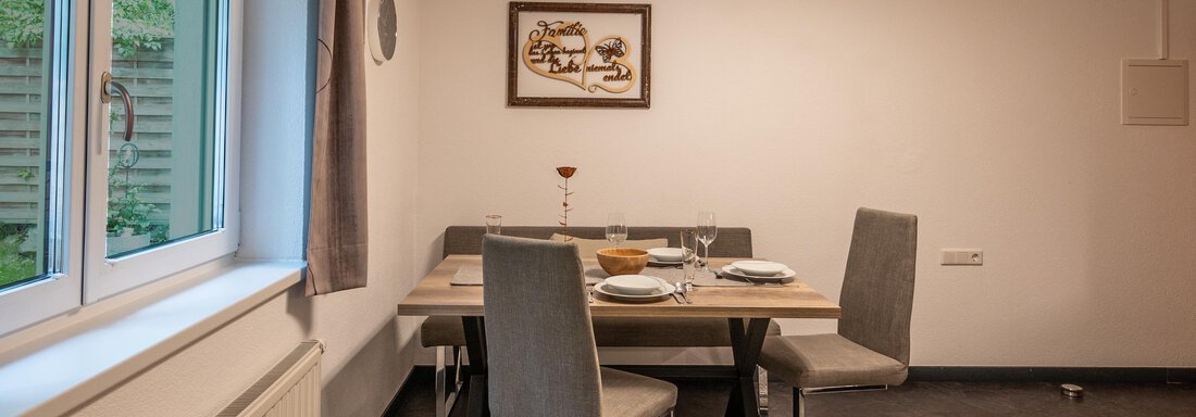 A cozy dining area with a wooden table and modern chairs. The window provides plenty of natural light and a pleasant atmosphere. - Apart Conny - Längenfeld