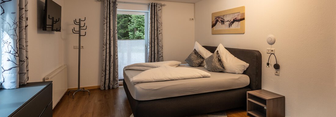 A cozy bedroom with a double bed and modern furniture.  
Large windows let in a lot of light and provide a view outside. - Apart Conny - Längenfeld