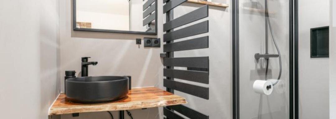 Badezimmer mit Dusche und WC A modern bathroom with an open shower and a stylish sink. The walls are in neutral colors and there are wooden accents. - Apartment DoLa - Längenfeld