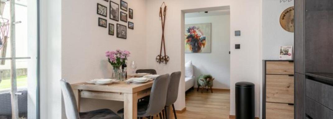A modern dining room with a wooden table and gray chairs. Pictures hang on the wall, and the atmosphere is bright and inviting. - Apartment DoLa - Längenfeld