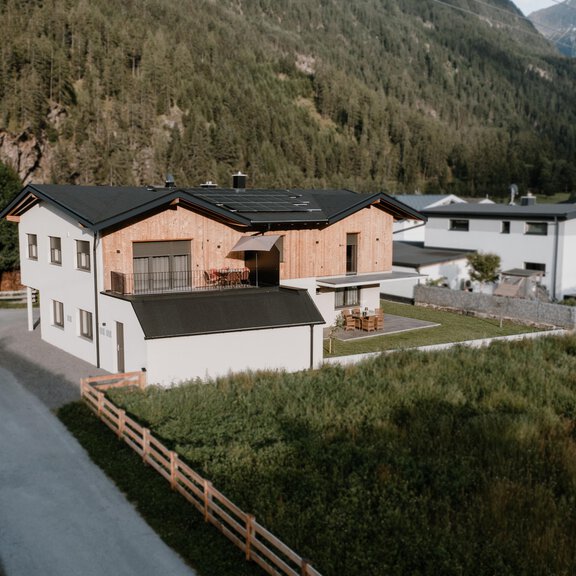 A modern house with wood cladding and a large garden. Surrounded by green meadows and mountains in the background. - Apartment Fernzeit - Längenfeld