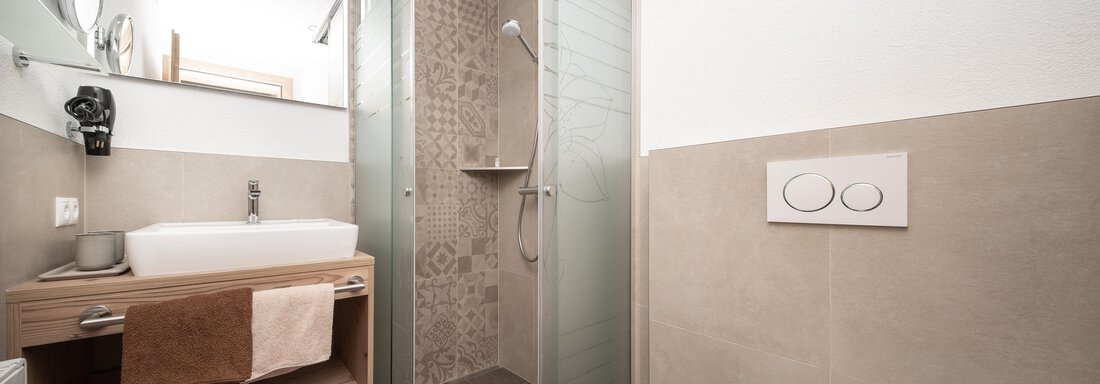 Ein modernes Badezimmer mit einer Dusche und einem Waschbecken. Wände und Boden sind in neutralen, hellen Tönen gestaltet. - Appart Klotz Alpenglück - Längenfeld