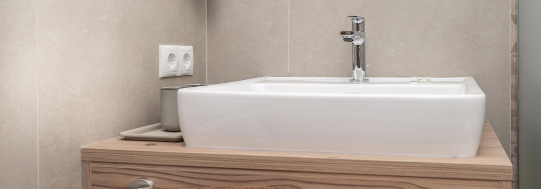 Ein modernes Badezimmer mit einem eleganten Waschbecken auf einem Holzuntergestell. Handtücher in neutralen Farben liegen bereit. - Appart Klotz Alpenglück - Längenfeld