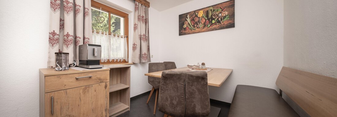 Ein gemütlicher Essbereich mit einem Holztisch und Stühlen. Das Zimmer hat helle Wände und Vorhänge mit floralen Mustern. - Appart Klotz Alpenglück - Längenfeld