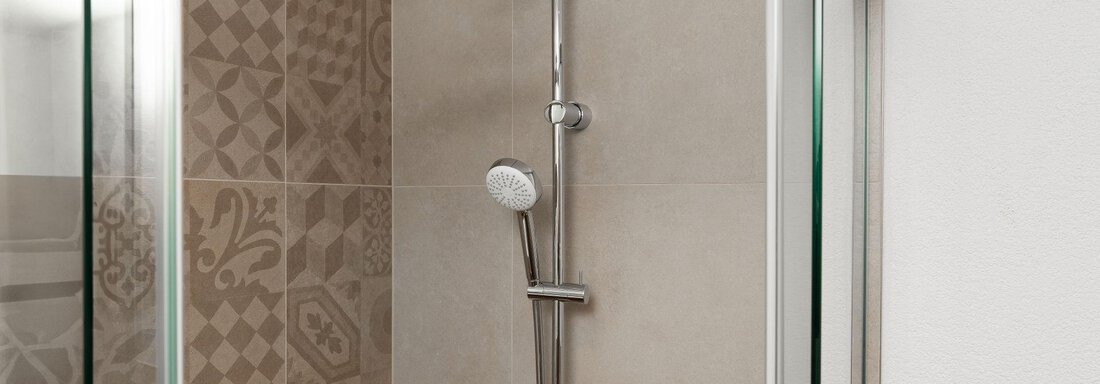 Eine moderne Dusche mit einem Regenduschkopf und einer gläsernen Abtrennung. Die Wände sind mit eleganten Fliesen in sanften Farben gestaltet. - Appart Klotz Alpenglück - Längenfeld