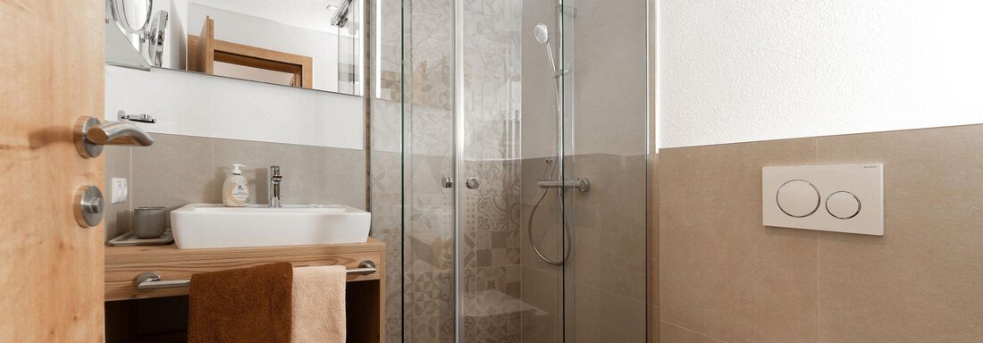 Ein modernes Badezimmer mit einer gläsernen Dusche und einem Waschbecken. Die Wände sind in neutralen Farbtönen gehalten und es gibt Holz- und Dekorationselemente. - Appart Klotz Alpenglück - Längenfeld