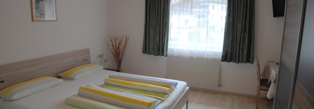 2. Schlafzimmer Appart Tanja A cozy bedroom with a double bed and light curtains. The room is simply and modernly furnished. - Appart Tanja - Längenfeld