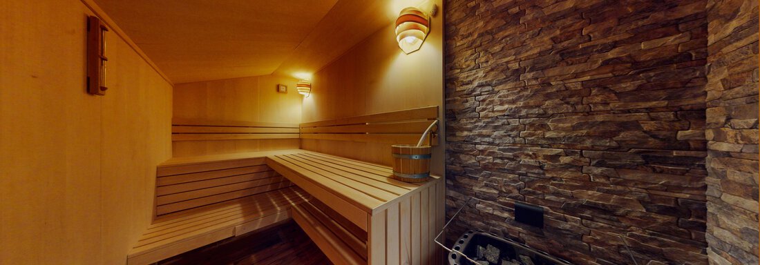 Eine gemütliche Sauna mit Holzbank und Steindekor. Sanftes Licht sorgt für eine entspannte Atmosphäre. - Das Berg Loft - Längenfeld