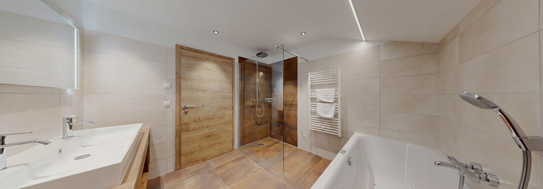 Ein modernes Badezimmer mit einer Badewanne und einer Dusche. Die Wände sind hell gefliest, und es gibt Holzakzente. - Das Berg Loft - Längenfeld
