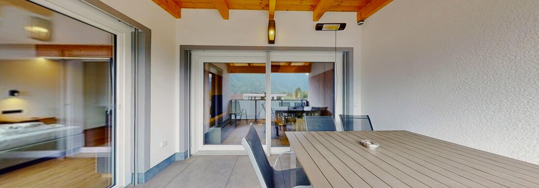 Ein schöner überdachter Balkon mit einem modernen Esstisch und Stühlen. Im Hintergrund sind große Fenster mit Blick auf eine ruhige Landschaft. - Das Berg Loft - Längenfeld