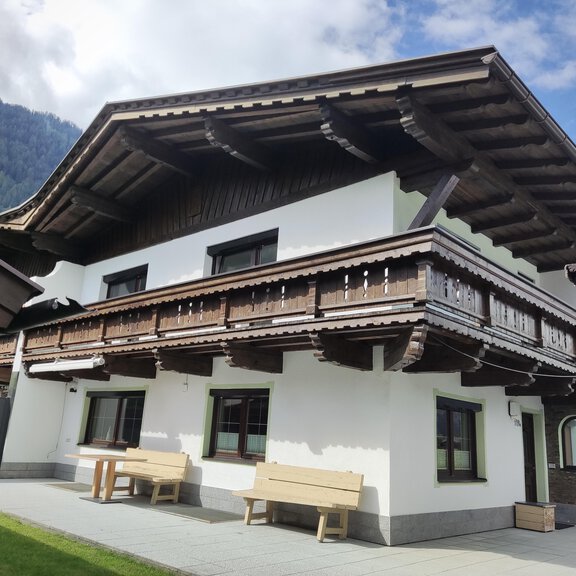 Ein traditionelles Haus mit Holzverkleidung und einem großen Balkon. Es liegt in einer malerischen Berglandschaft. - Ferienhaus Tami - Längenfeld