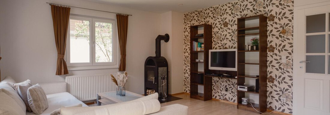 A cozy living space with a bright sofa and a decorative wall. A fireplace and a television complement the modern decor. - Haus Margret - Längenfeld