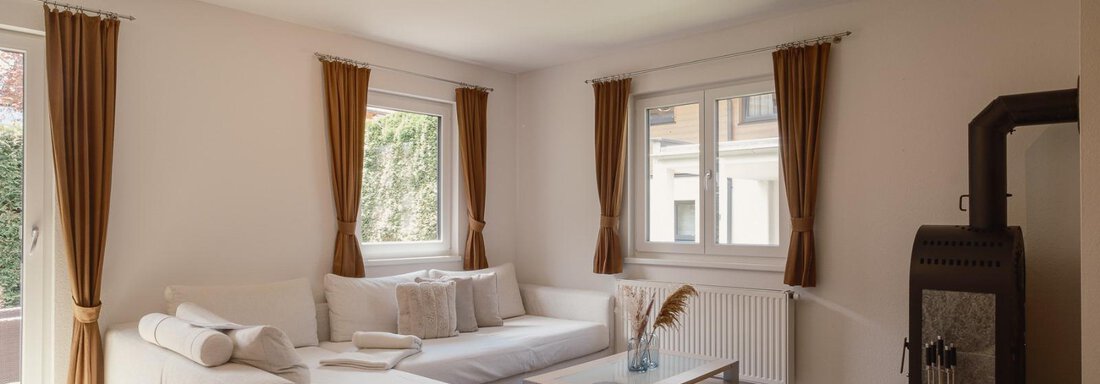 A modern living room with a white sofa and a table. Large windows let in plenty of daylight. - Haus Margret - Längenfeld