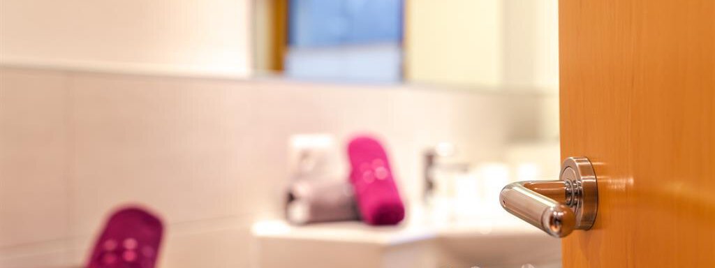 A door leading to a modern bathroom.  
In the room, towels in purple and gray are ready. - Haus Viktoria - Längenfeld