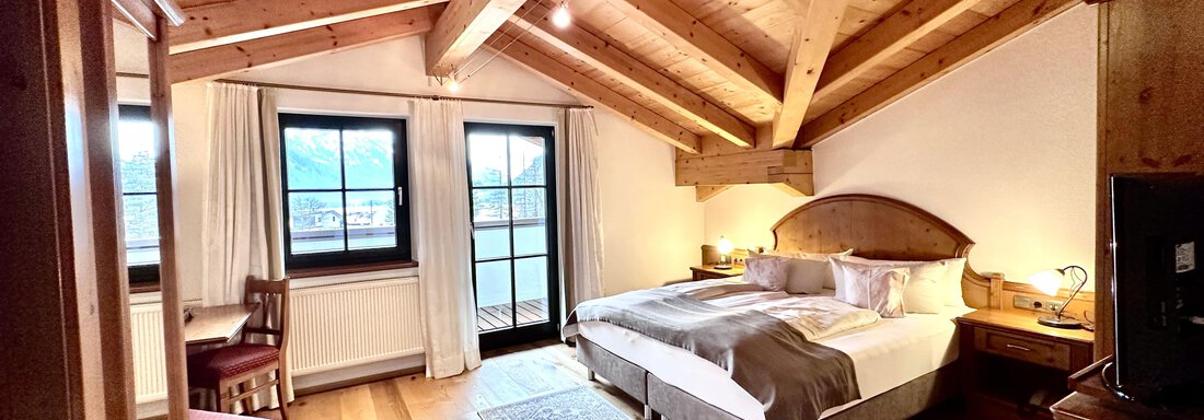 Ein gemütliches Schlafzimmer mit Holzdecke und großen Fenstern. Das Zimmer ist modern eingerichtet und bietet viel Tageslicht. - Hotel Stern - Längenfeld