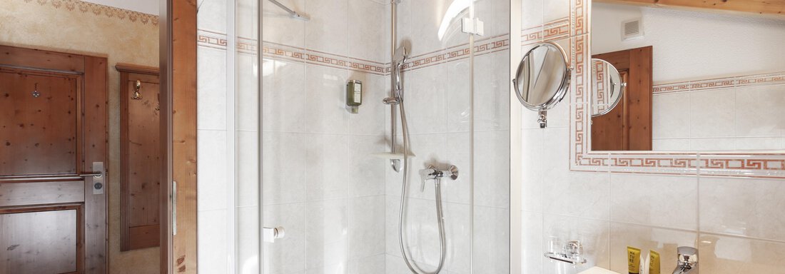 Ein modernes Badezimmer mit einer gläsernen Dusche und einem Waschbecken. Die Wände sind hell und mit Holzelementen ausgestattet. - Hotel Stern - Längenfeld