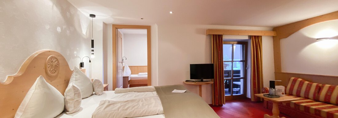 Ein gemütliches Hotelzimmer mit einem Doppelbett und dekorativen Kissen. Der Raum hat warme Farben und ein großes Fenster mit Blick nach draußen. - Hotel Stern - Längenfeld