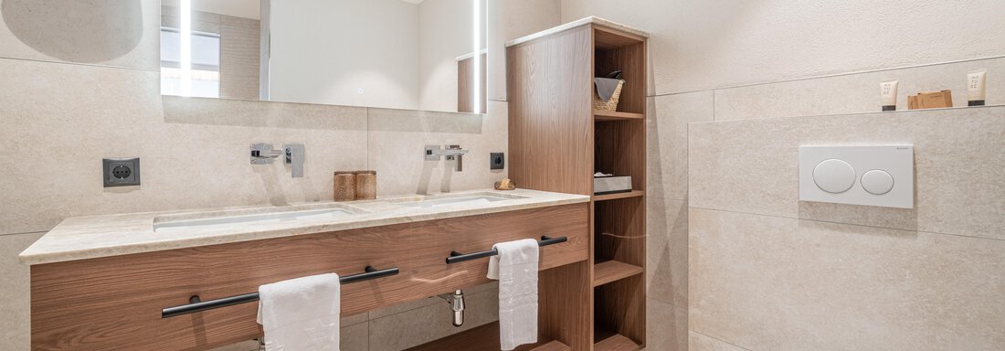 Ein modernes Badezimmer mit einem Holzwaschtisch und großen Spiegel. Die Wände sind hell und die Ausstattung ist stylish und funktional. - Hotel Stern - Längenfeld