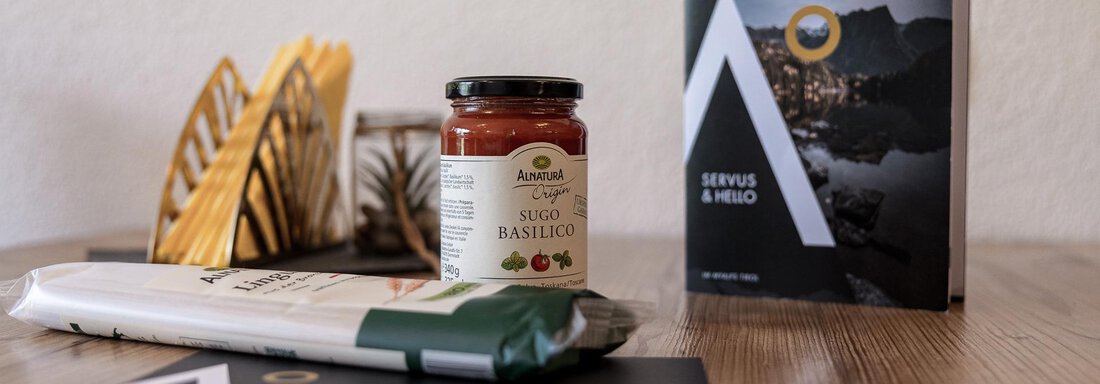 A stylishly set table with a jar of pesto, a herb product, and a bound notebook. Decorative elements are visible in the background. - MYALPS Himmelreich - Längenfeld